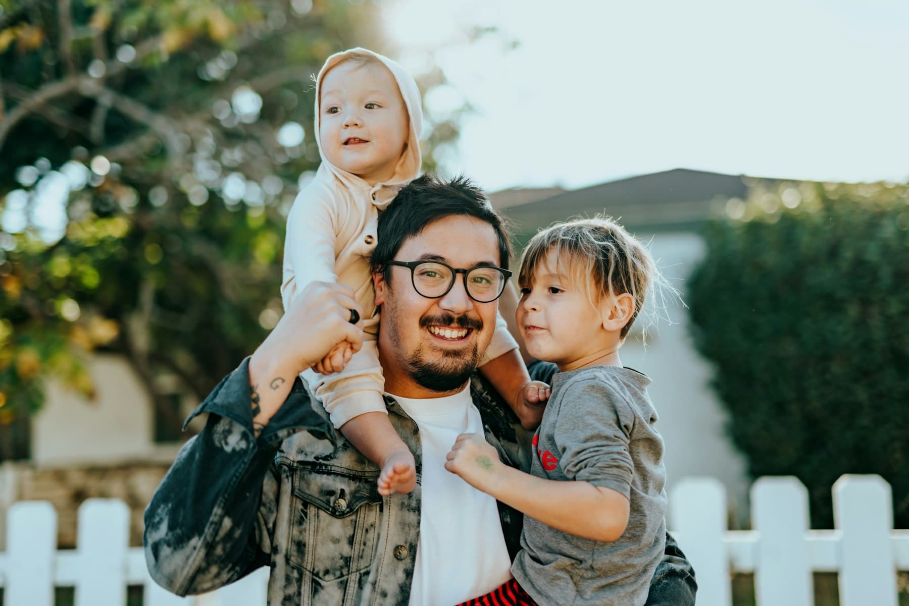 Padre cargando a sus dos hijos pequeños al aire libre